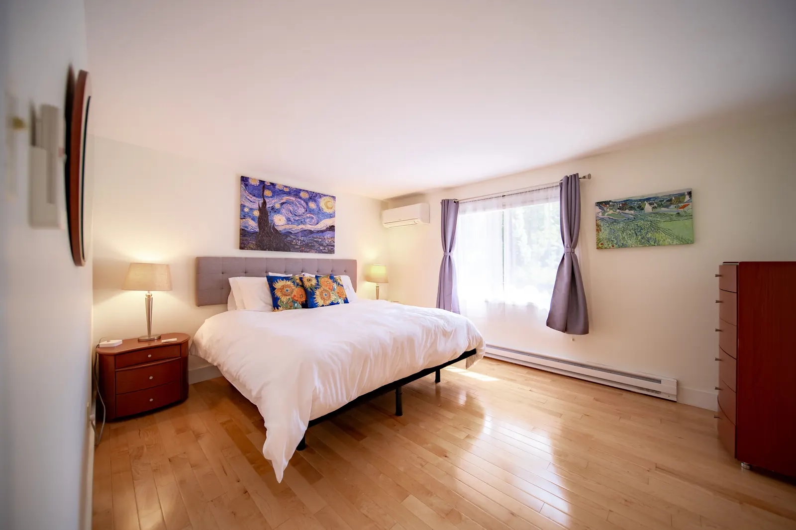 Guest bedroom at Lakeside Landing FLX — king bed on hardwood floors, Van Gogh reproductions on cream walls