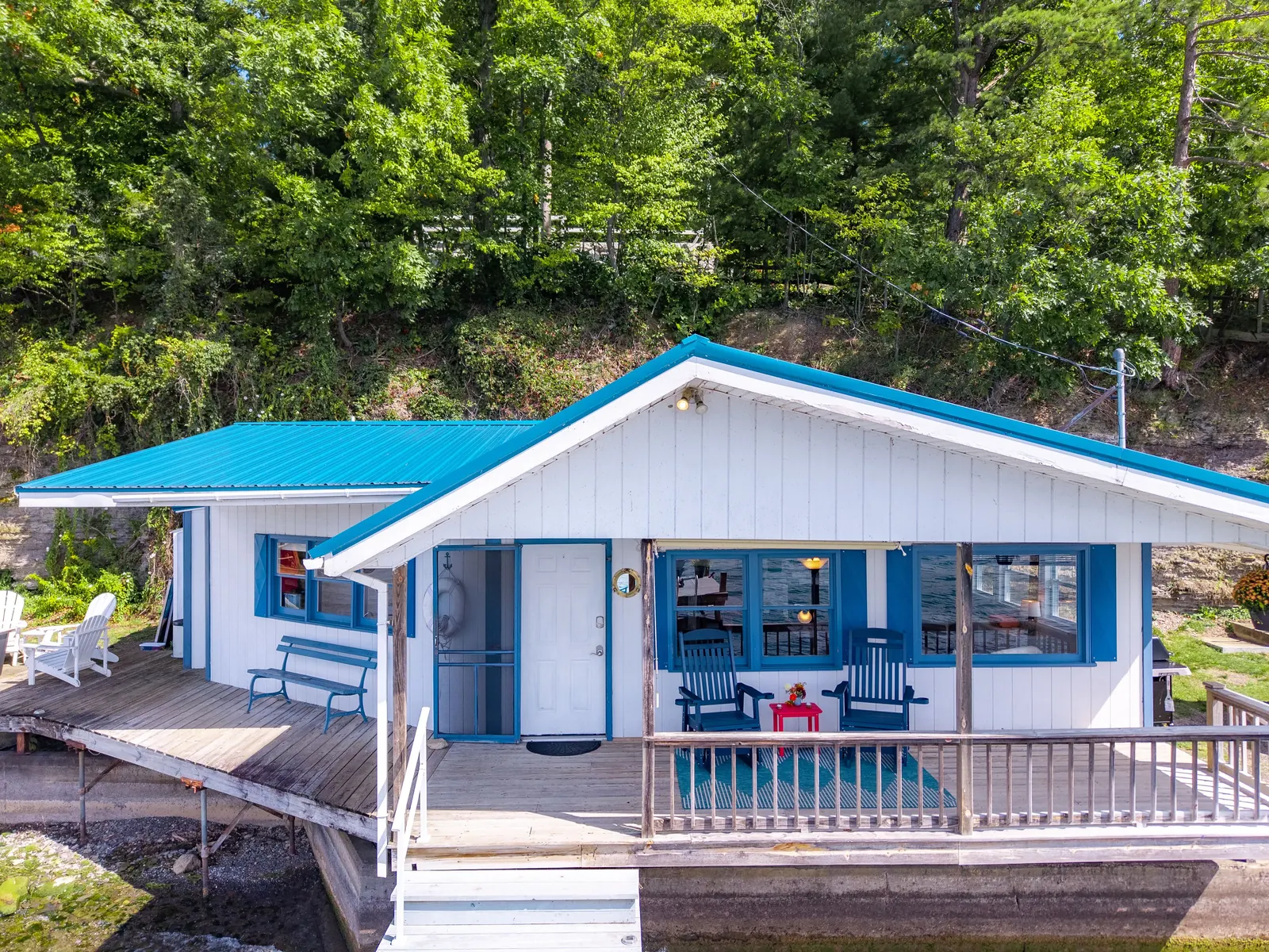 Smooth Sailing FLX — the waterfront cottage from the lake, blue-and-white board-and-batten with a covered porch on the dock