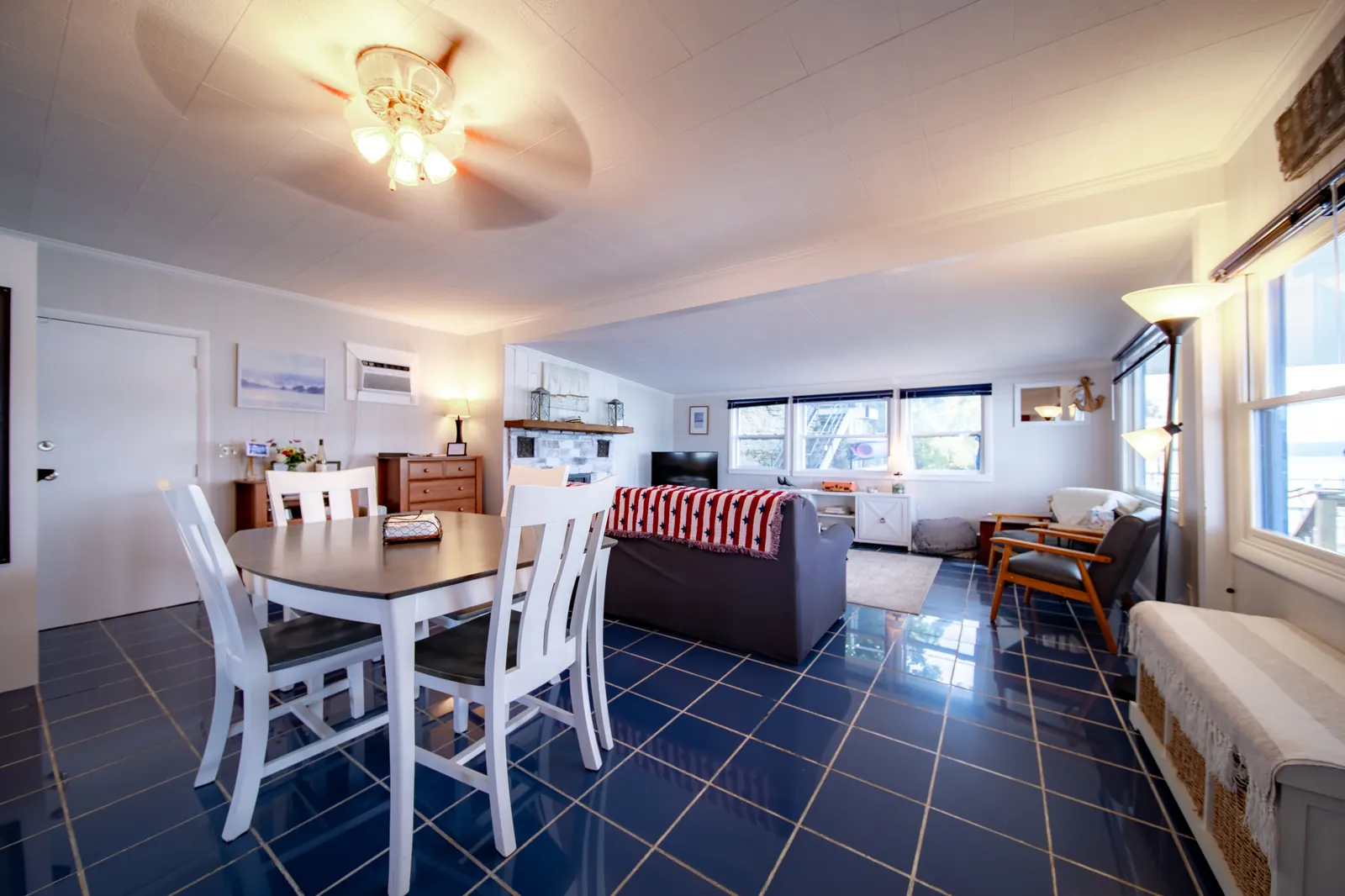 The main room at Smooth Sailing FLX — open-plan living and dining, blue tile floor, ceiling fan, big windows facing the lake